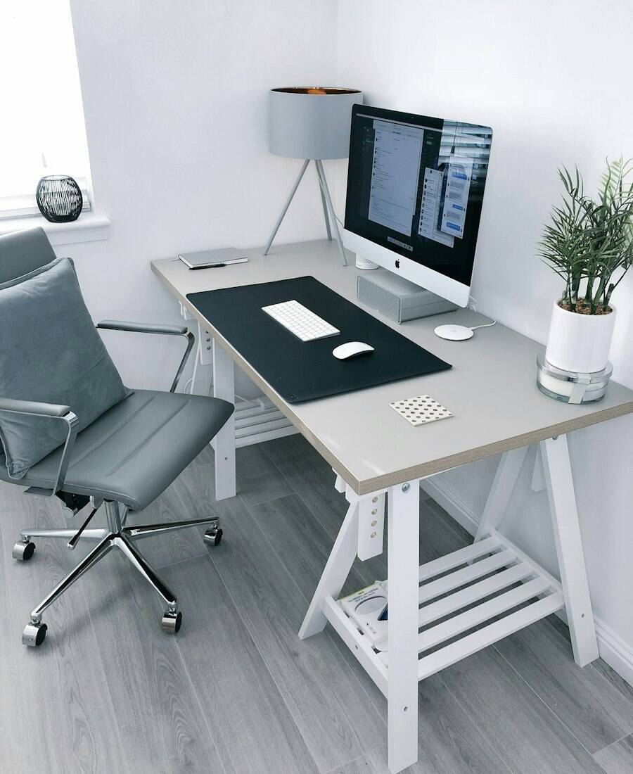 A clean home office with a white desk, chair and desk lamp.